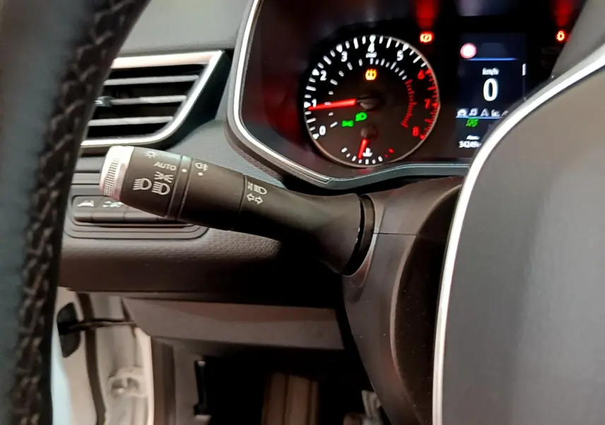 Gros plan sur le commodo gauche et le tableau de bord éclairé de la Renault Clio Business TCe 100 blanche de 2020.