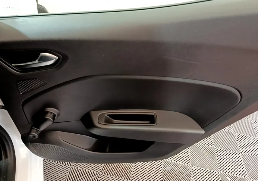 Détail de la porte intérieure côté gauche d'une Renault Clio Business blanche, avec poignée et commande manuelle de vitre.