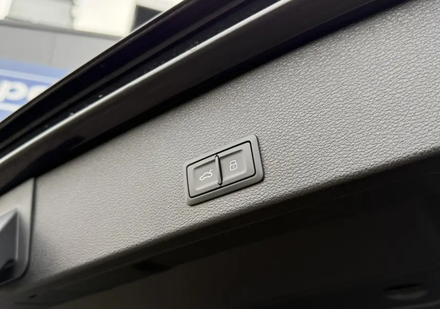 Boutons de hayon électrique et verrouillage intégrés au panneau intérieur du coffre d'un Audi Q2 noir Mythe 2023.