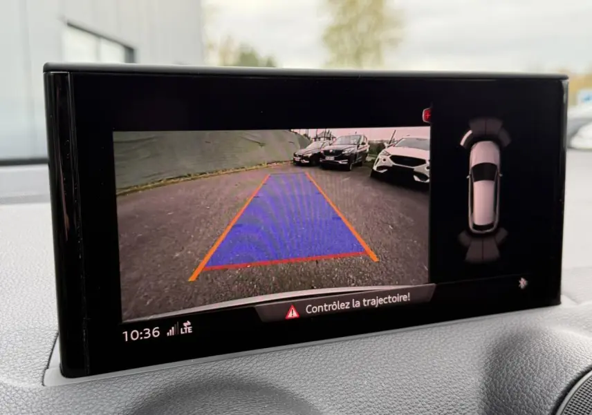 Affichage caméra de recul de l'Audi Q2 noir Mythe, vue arrière avec lignes de guidage et alertes de trajectoire.