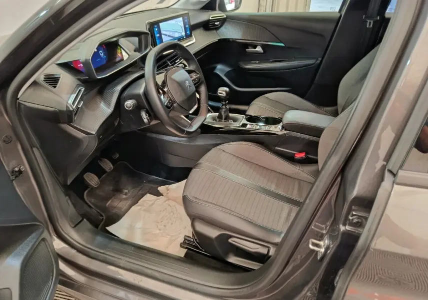 Intérieur avant droit de Peugeot 208 2020 gris, volant cuir multifonctions, écran tactile et tableau de bord numérique.