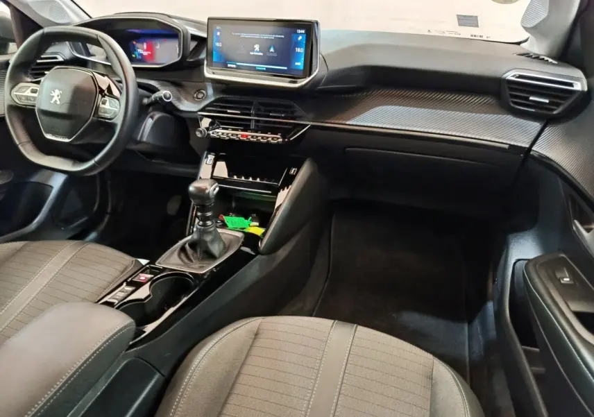Intérieur de la Peugeot 208 BlueHDi 100 S&S Allure Business 2020, vue côté passager avec tableau de bord et volant cuir noir.