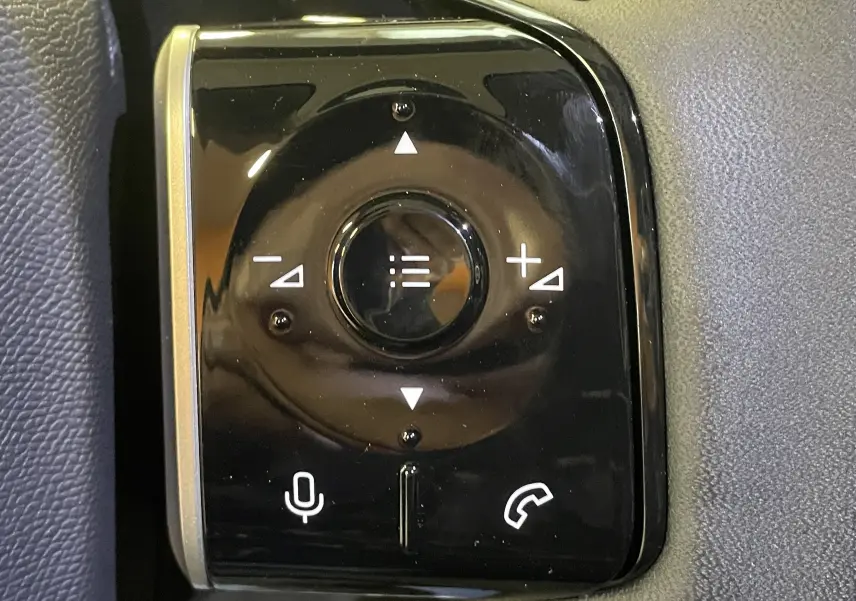 Gros plan sur les commandes au volant noir brillant du Citroën C5 Aircross hybride 2026, avec boutons de volume et téléphone.