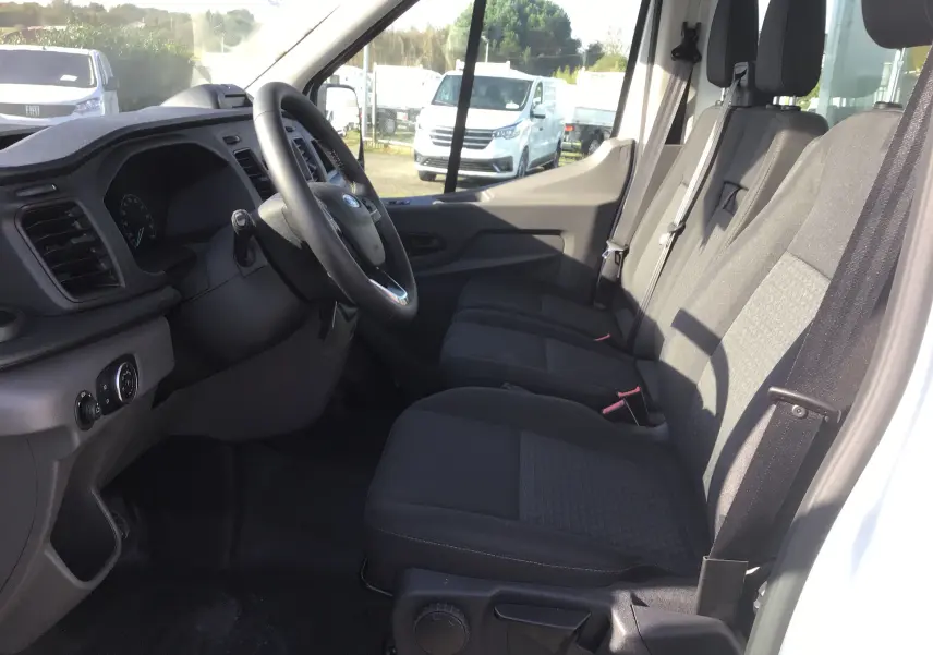 Vue intérieure côté conducteur du Ford Transit Chassis Cabine blanc, montrant les sièges avant et le tableau de bord simple.