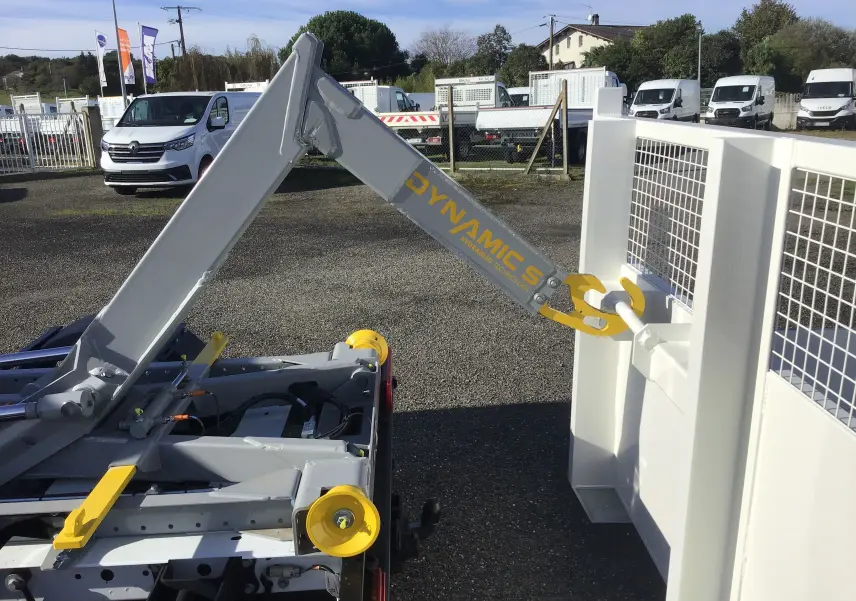 Gros plan sur le bras polybenne gris et jaune du Ford Transit Chassis cabine blanc, vu de l'arrière côté droit.