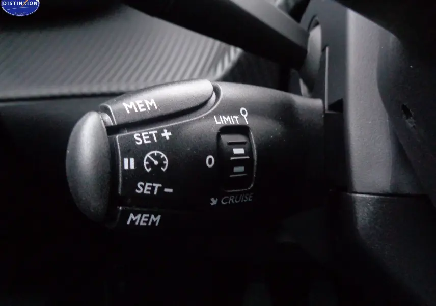 Gros plan sur la commande de régulateur de vitesse du Peugeot 2008 2023, intérieur noir avec détails blancs.