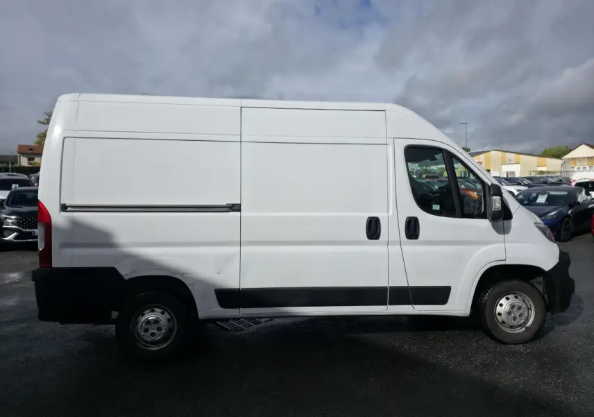 Vue de profil côté gauche d'un fourgon Opel Movano blanc avec panneaux latéraux lisses et bas de caisse noir.