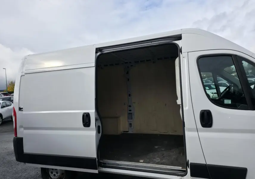 Vue latérale droite d'un Opel Movano Fourgon blanc avec porte coulissante ouverte montrant l'intérieur bois.