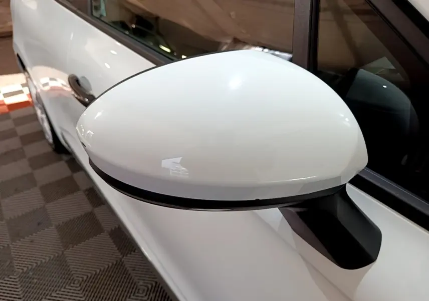 Rétroviseur blanc côté conducteur d'une Renault Clio Business 2021, avec carrosserie blanche visible en arrière-plan.