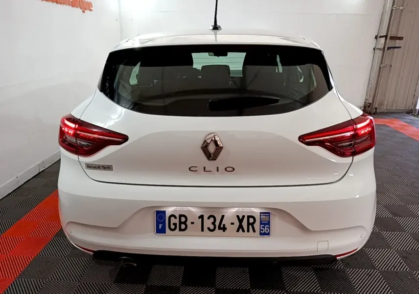 Vue arrière d'une Renault Clio blanche 2021 avec feux LED et logo central bien visibles dans un garage.