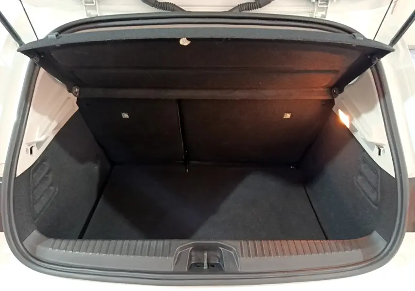 Coffre ouvert vu de l'arrière d'une Renault Clio Business blanche, intérieur noir et éclairage latéral droit.