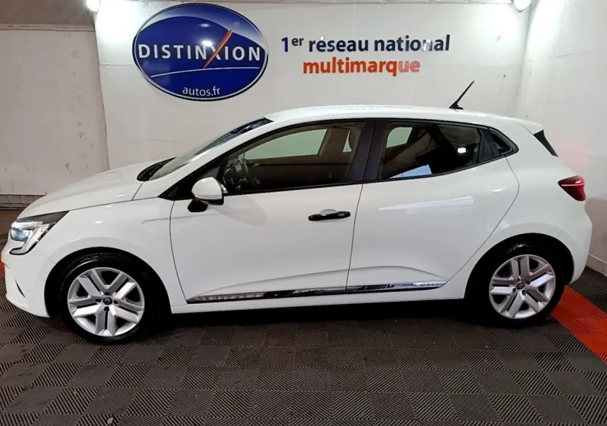 Profil droit d'une Renault Clio Business blanche 2021, avec jantes alliage et poignées de porte noires, en intérieur showroom.