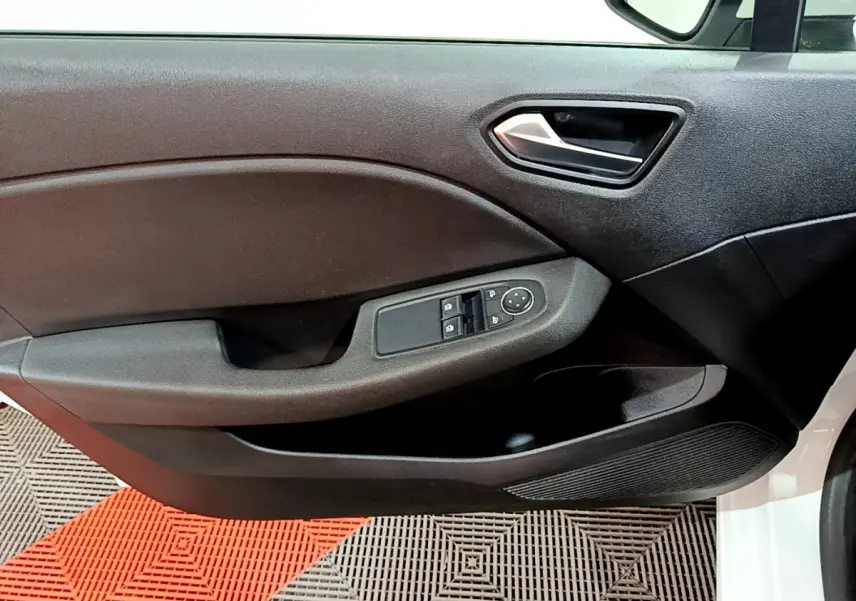 Vue rapprochée de la porte avant gauche d’une Renault Clio Business blanche, avec commandes électriques des vitres et rétroviseurs.