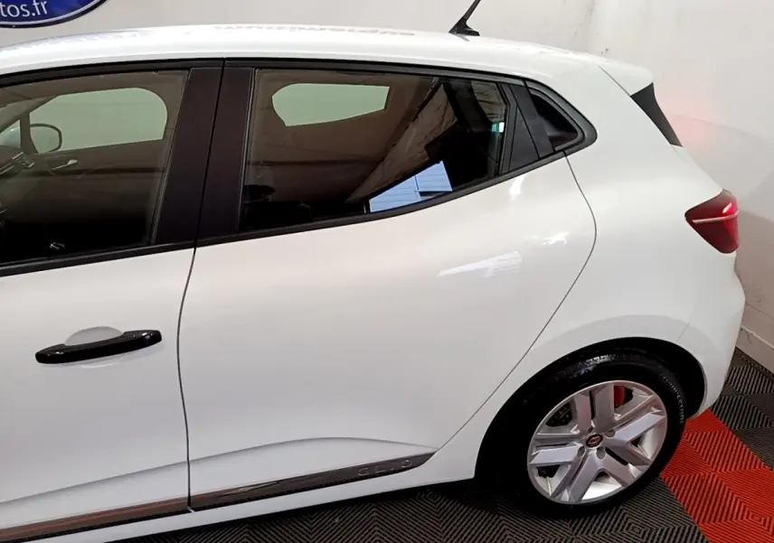 Vue latérale côté gauche d'une Renault Clio blanche avec poignées noires et jantes alliage argentées.