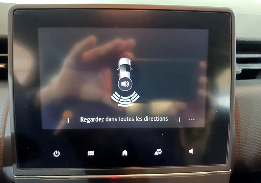 Écran tactile central de la Renault Clio Business blanc, affichant l'alerte de détection d'obstacles arrière.