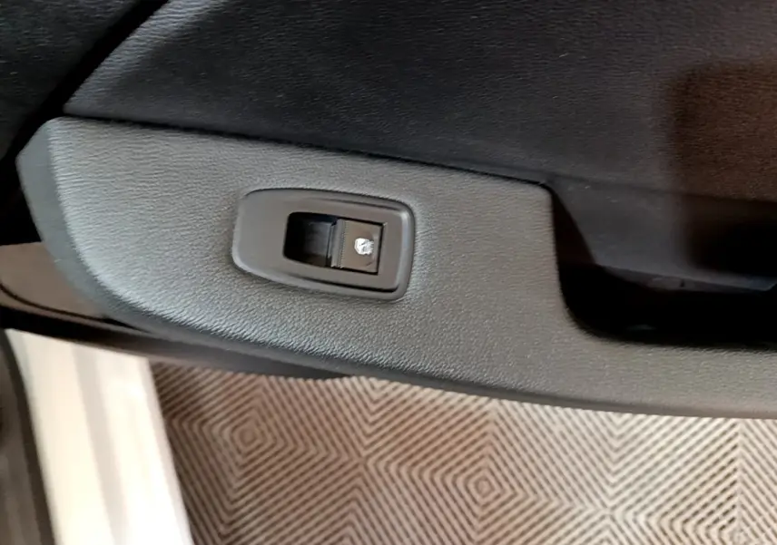 Gros plan sur la commande de verrouillage de porte noire dans l’intérieur côté gauche d’une Renault Clio Business blanche.