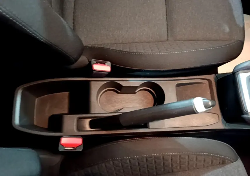 Vue plongeante sur la console centrale noire de la Renault Clio Business avec frein à main manuel et sièges tissu gris foncé.