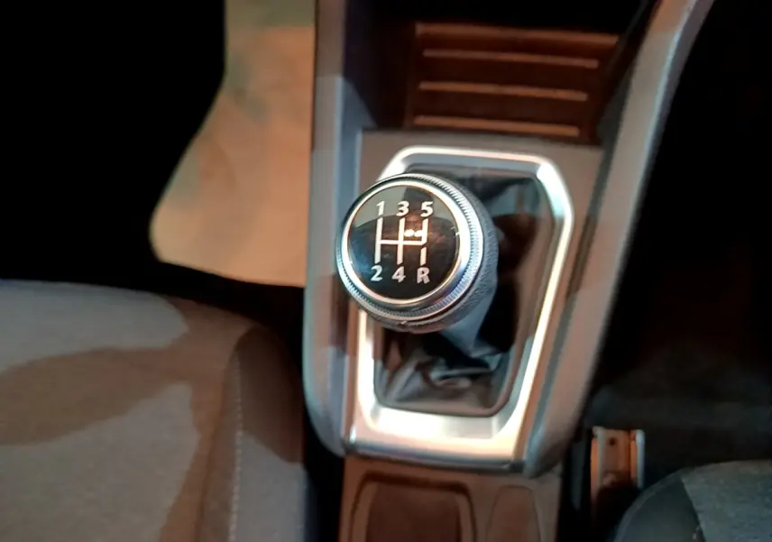 Gros plan sur le levier de vitesse manuel noir et argenté de la Renault Clio Business blanche, intérieur sombre.