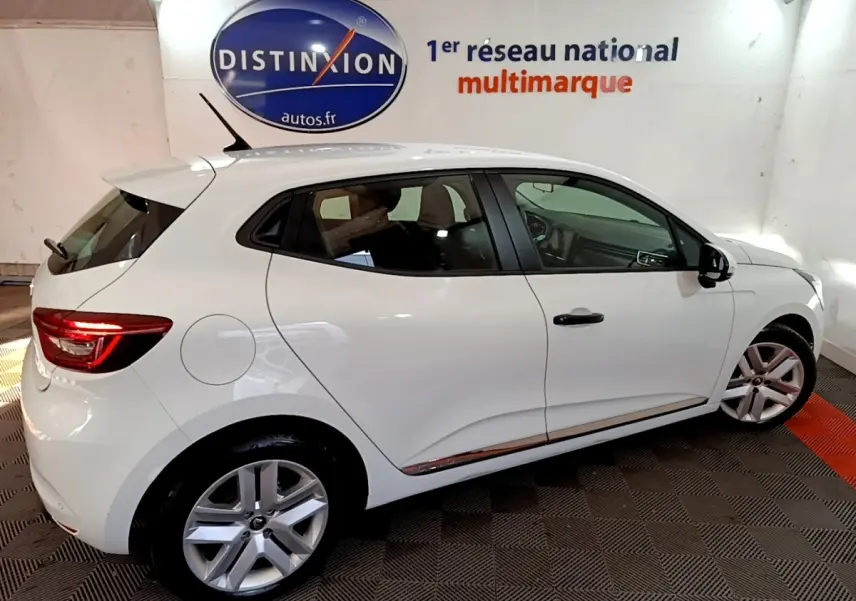 Renault Clio Business blanc vue côté droit en intérieur, avec jantes alliage et feux arrière LED allumés.