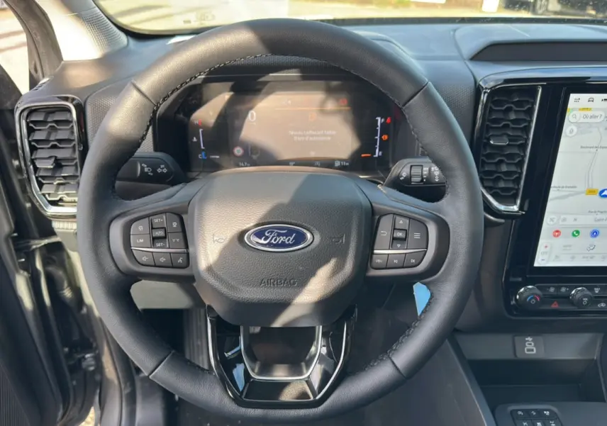 Vue rapprochée du volant en cuir noir du Ford Ranger 2026 avec tableau de bord numérique et écran tactile GPS.