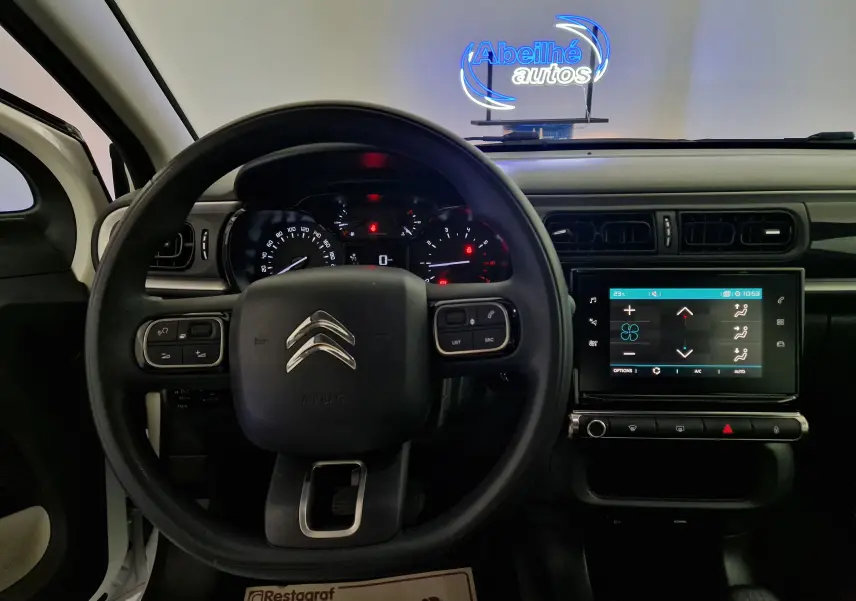 Vue intérieure centrée sur le volant et le tableau de bord d'une Citroën C3 Société blanche avec écran tactile allumé.