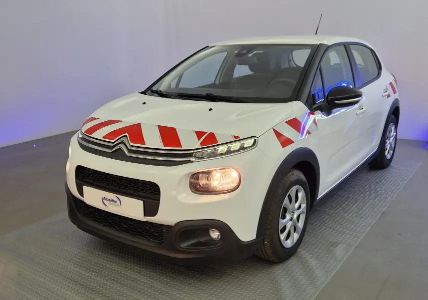 Vue 3/4 avant droite d'une Citroën C3 Société blanche avec bandes rouges de signalisation sur capot et ailes.