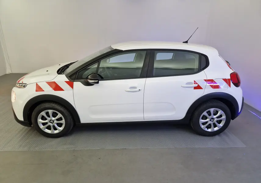 Vue de profil côté gauche d'une Citroën C3 blanche avec bandes rouges diagonales sur l'aile avant et arrière.
