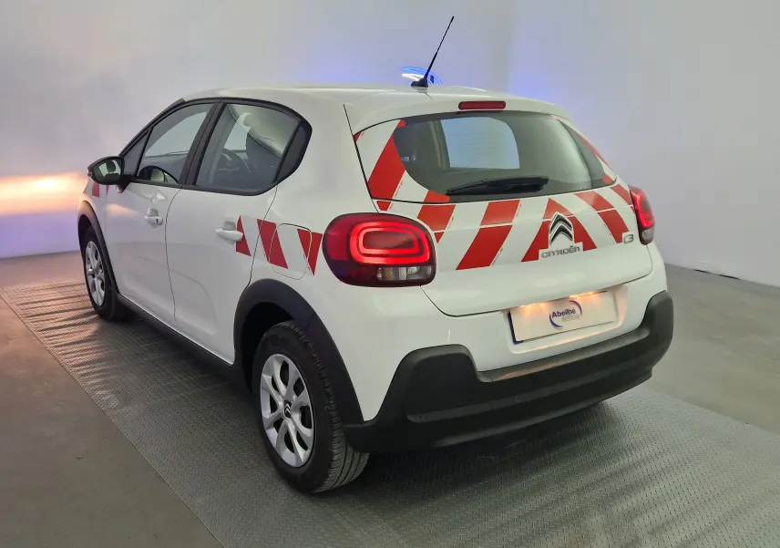 Vue 3/4 arrière droite d'une Citroën C3 Société blanche de 2019 avec bandes rouges diagonales sur la partie arrière.