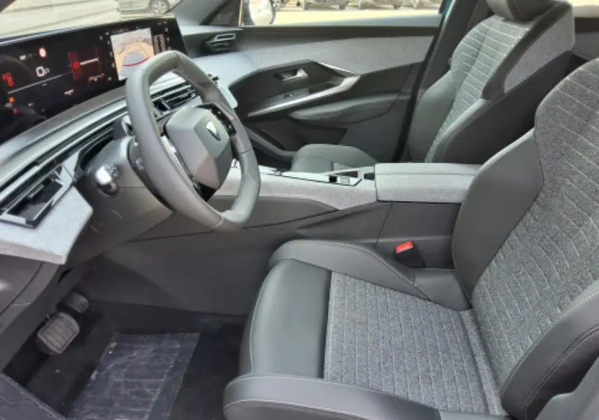 Vue intérieure côté conducteur du Peugeot 3008 Hybrid 2026, avec sièges gris et tableau de bord numérique panoramique.
