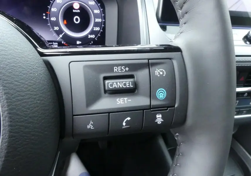 Gros plan sur les commandes du volant cuir noir du Nissan Qashqai 1.5 e-Power 2025 avec affichage numérique au tableau de bord.