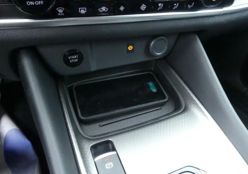 Détail de la console centrale du Nissan Qashqai 2025 avec chargeur à induction et bouton Start/Stop visible.