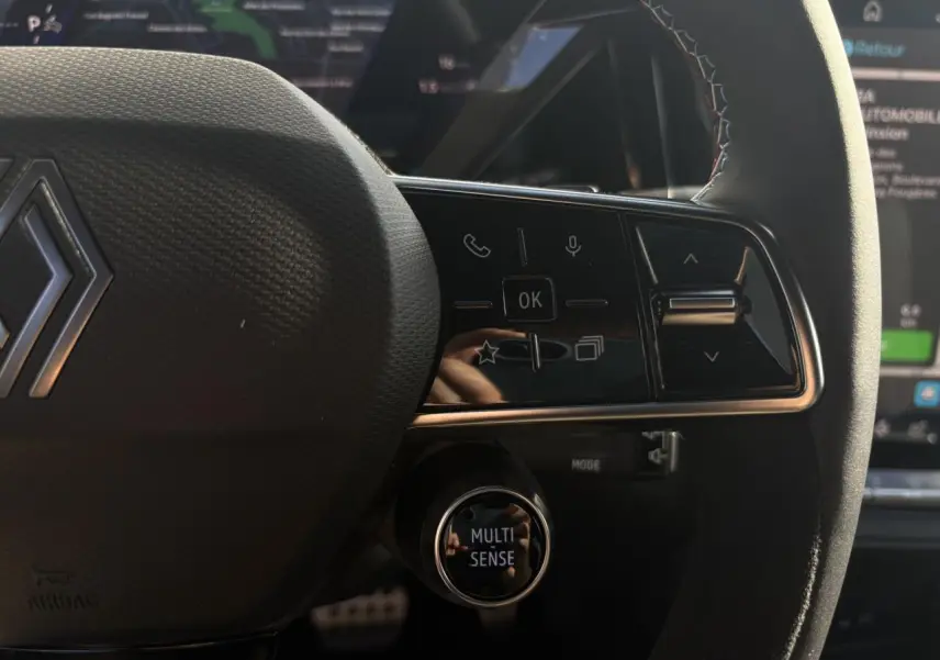 Gros plan sur le volant Alcantara avec surpiqûres tricolores et commandes multifonctions du Renault Rafale E-Tech Gris Schiste.