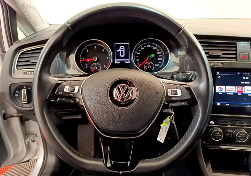 Vue rapprochée du volant cuir noir de la Volkswagen Golf 2019 avec tableau de bord et écran tactile allumé.