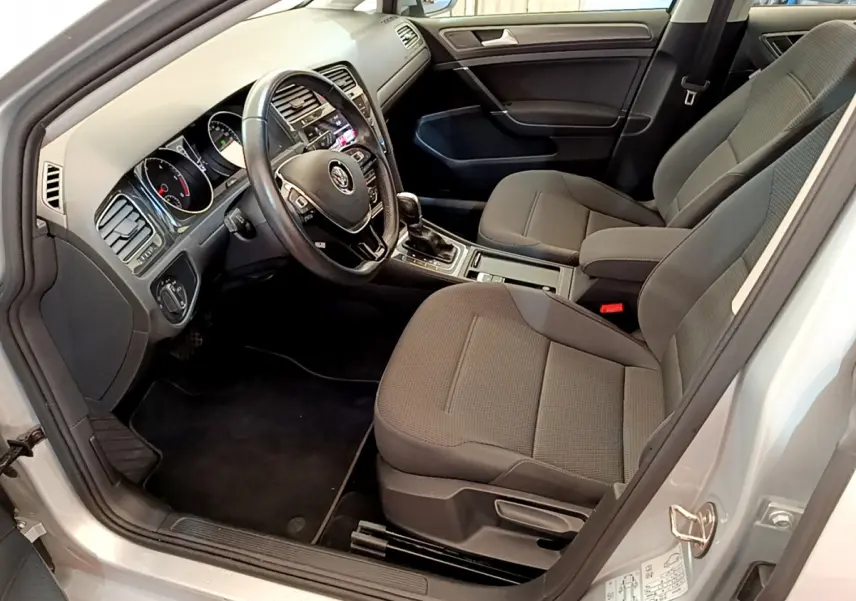 Intérieur de la Volkswagen Golf gris clair 2019, vue côté conducteur montrant sièges et tableau de bord avec volant cuir.