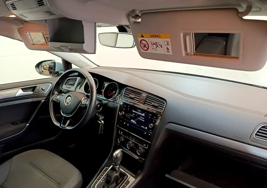 Intérieur avant droit de la Volkswagen Golf gris clair 2019, volant cuir, écran tactile et tableau de bord visible.