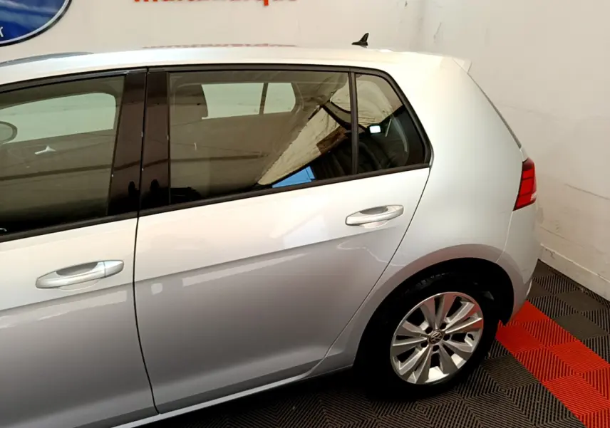 Vue côté droit arrière d'une Volkswagen Golf gris clair 2019 avec jante alliage et vitres teintées.