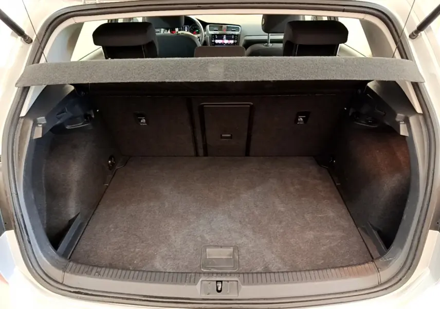 Coffre ouvert d'une Volkswagen Golf gris clair 2019, vue arrière montrant l'espace de chargement et la tablette arrière.