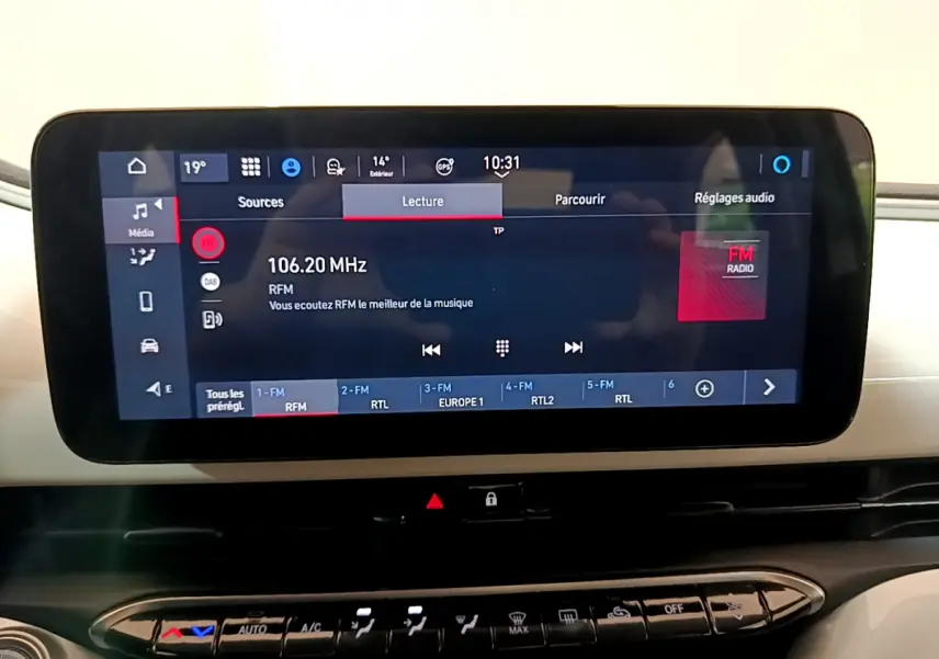 Écran tactile central affichant la radio FM dans l'habitacle blanc d'une Fiat 500 électrique Icône 2022.