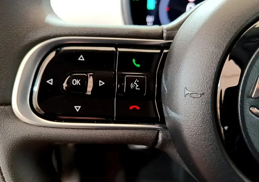 Gros plan sur les commandes gauche du volant noir de la Fiat 500 électrique blanche version 42kWh Icône 2022.