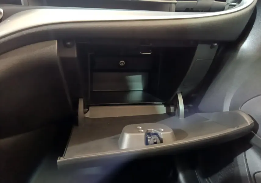 Gros plan sur la boîte à gants ouverte côté passager de la Fiat 500 électrique blanche, intérieur noir.