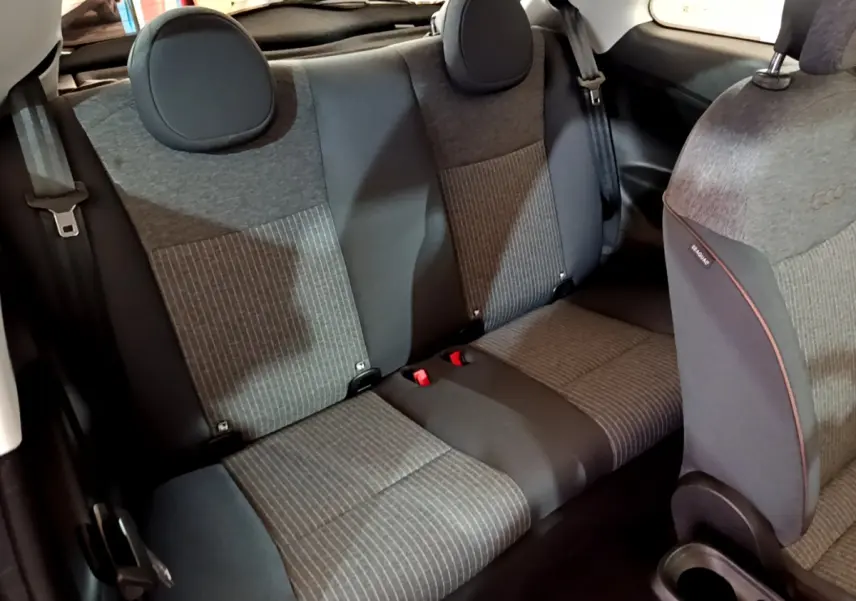 Vue intérieure arrière des sièges gris foncé et noir de la Fiat 500 42kWh Icône électrique 2022 avec appuie-têtes ronds.