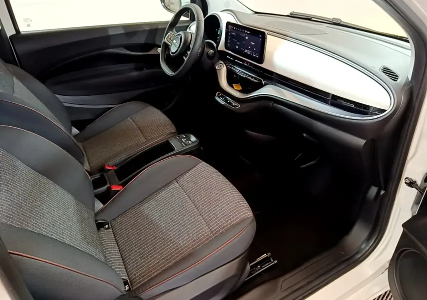 Intérieur avant droit de la Fiat 500 Icône 42kWh 2022 blanc, tableau de bord blanc et sièges gris à surpiqûres rouges