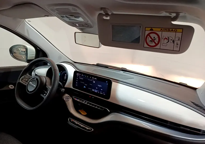 Intérieur avant droit de la Fiat 500 électrique blanche 2022, tableau de bord blanc brillant avec écran tactile central.