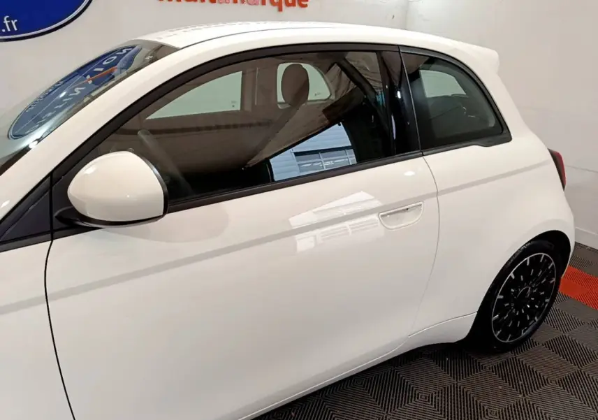Profil côté gauche d'une Fiat 500 électrique blanche, mettant en valeur sa silhouette compacte et ses jantes noires design.