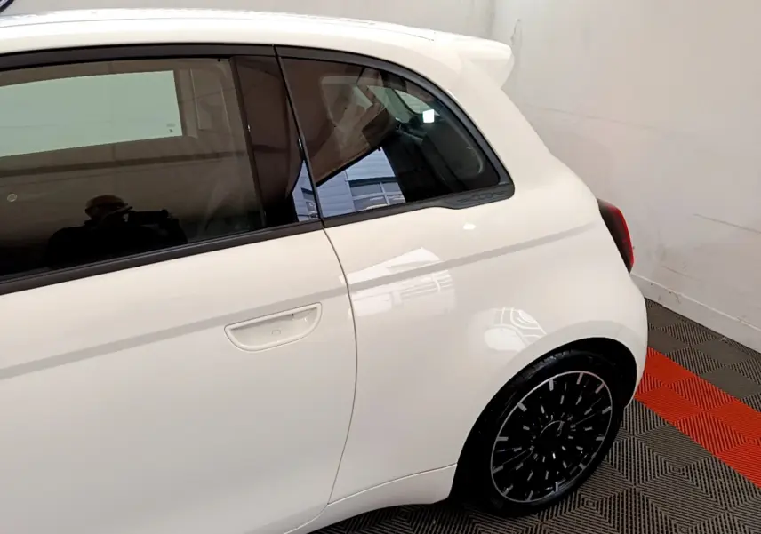 Vue côté droit arrière d'une FIAT 500 électrique blanche 42kWh Icône avec jante noire et logo 500 sur montant arrière.