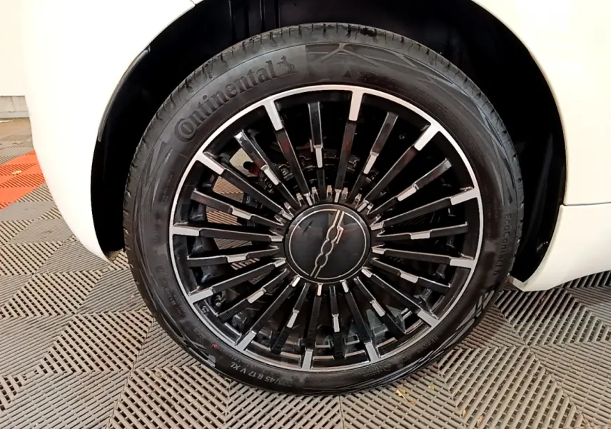 Gros plan sur la jante noire et argentée de la roue avant droite d'une FIAT 500 blanche électrique 2022 Icône.