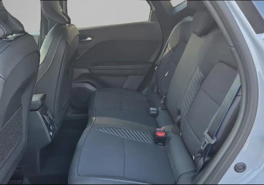 Vue intérieure arrière droite du Renault Captur E-Tech hybride 2025 avec sièges en tissu noir et ceinture grise.