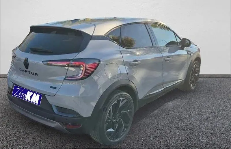 Vue 3/4 arrière droite du Renault Captur E-Tech hybride gris Rafale avec toit gris et jantes noires.