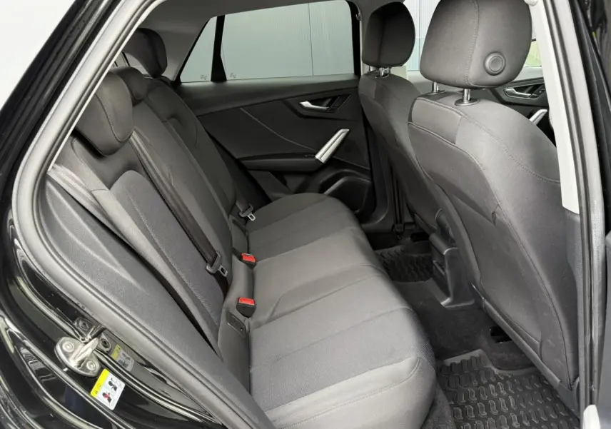 Vue intérieure côté droit montrant la banquette arrière grise du SUV Audi Q2 noir Mythe 2023.