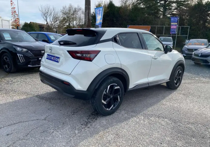 Nissan Juke blanc perle vu en 3/4 arrière droit, avec jantes noires et toit noir contrastant.
